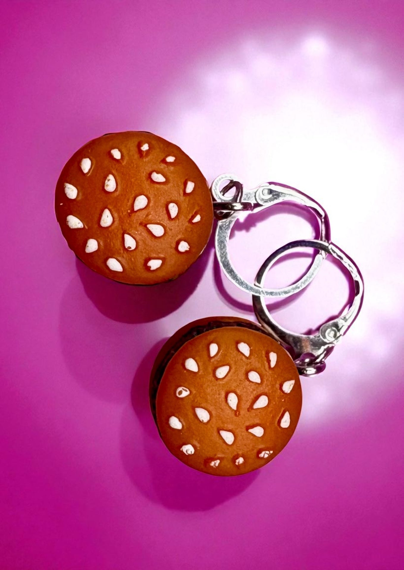 Hamburger-shaped earrings on a pink background