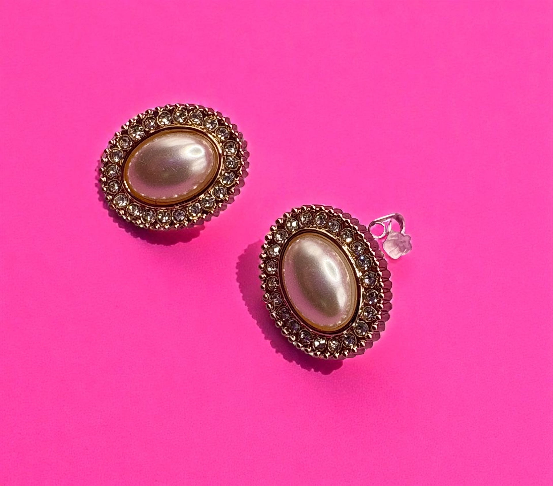 Pair of earrings with pearl-like centers on a pink background