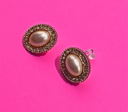 Pair of earrings with pearl-like centers on a pink background