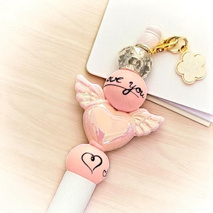 Pink candy-shaped keychain with 'love you' text on a light surface