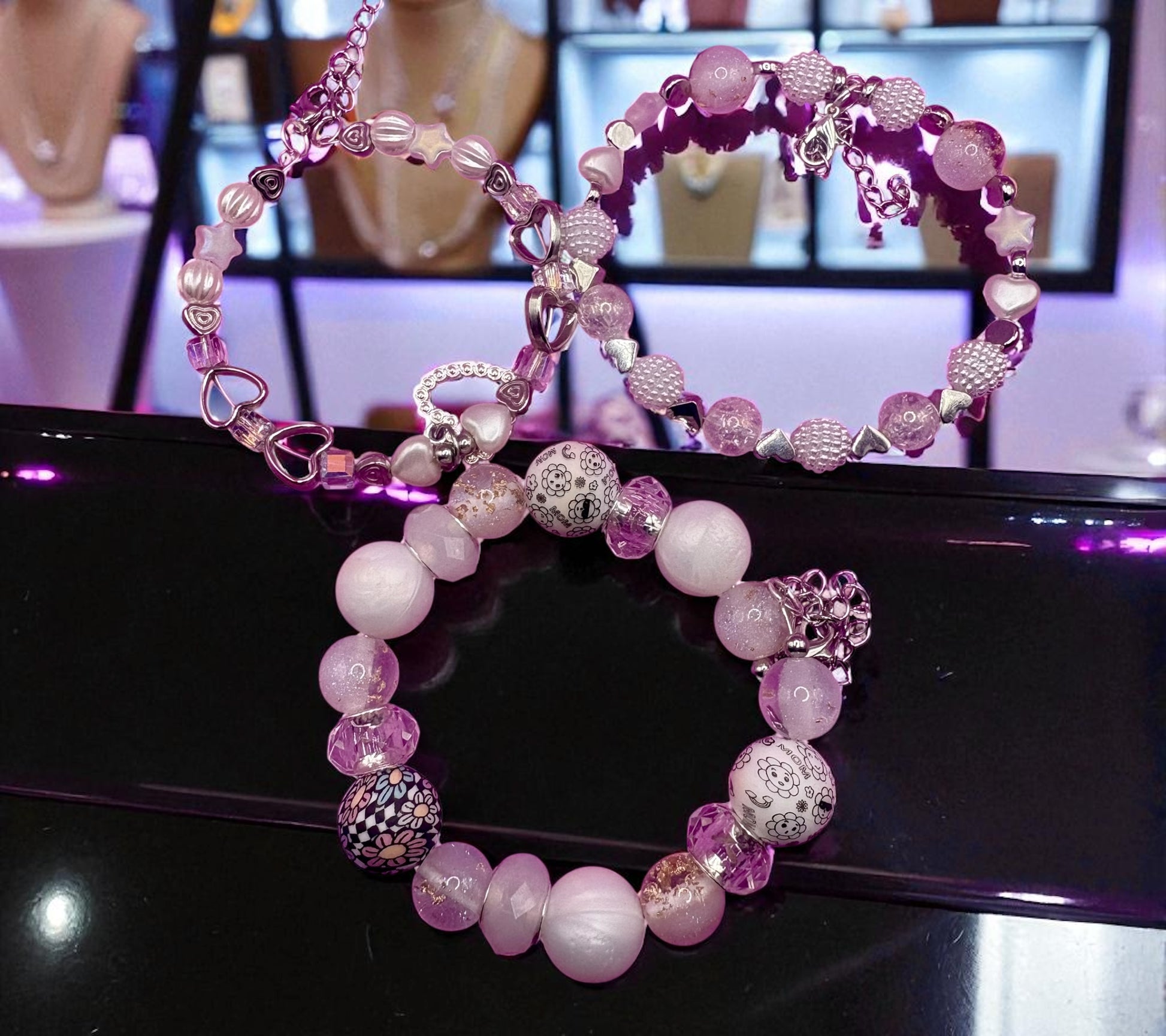 Pink and silver beaded bracelet on a black surface with blurred jewelry store background