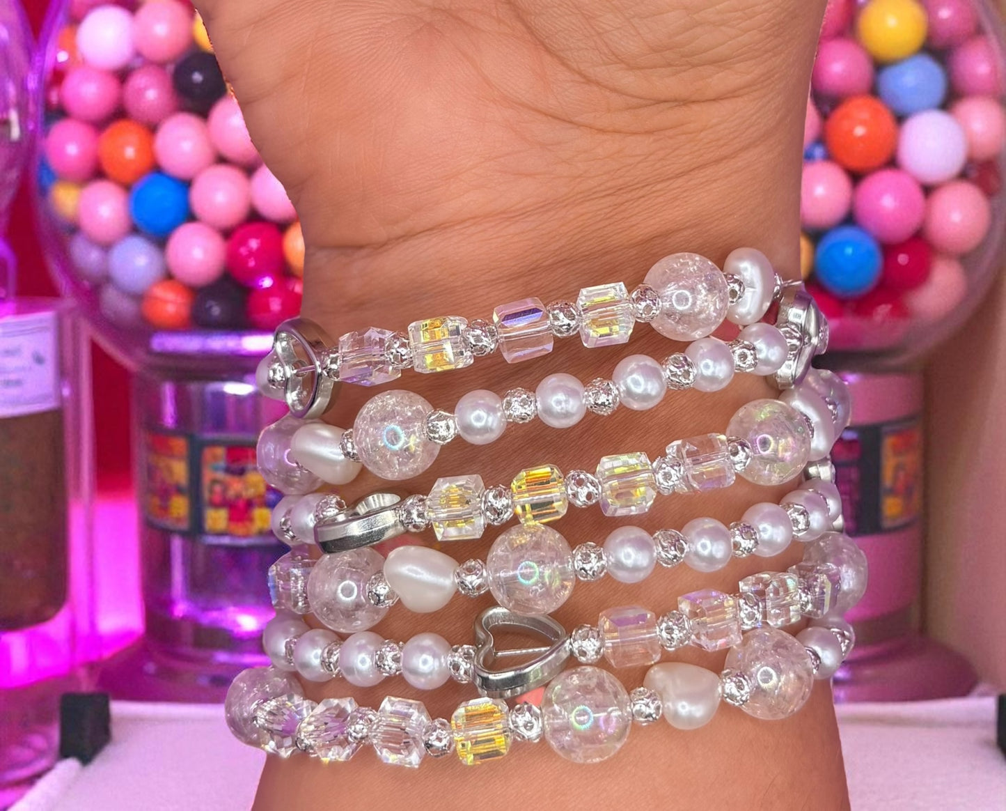 Stack of beaded bracelets on a wrist with colorful gumball machine in the background