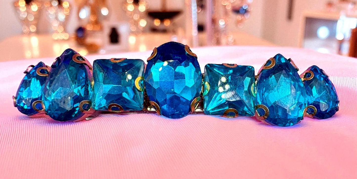 Set of blue gemstones with gold accents on a pink surface