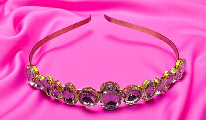 Decorative headband with pink gemstones on a pink fabric background