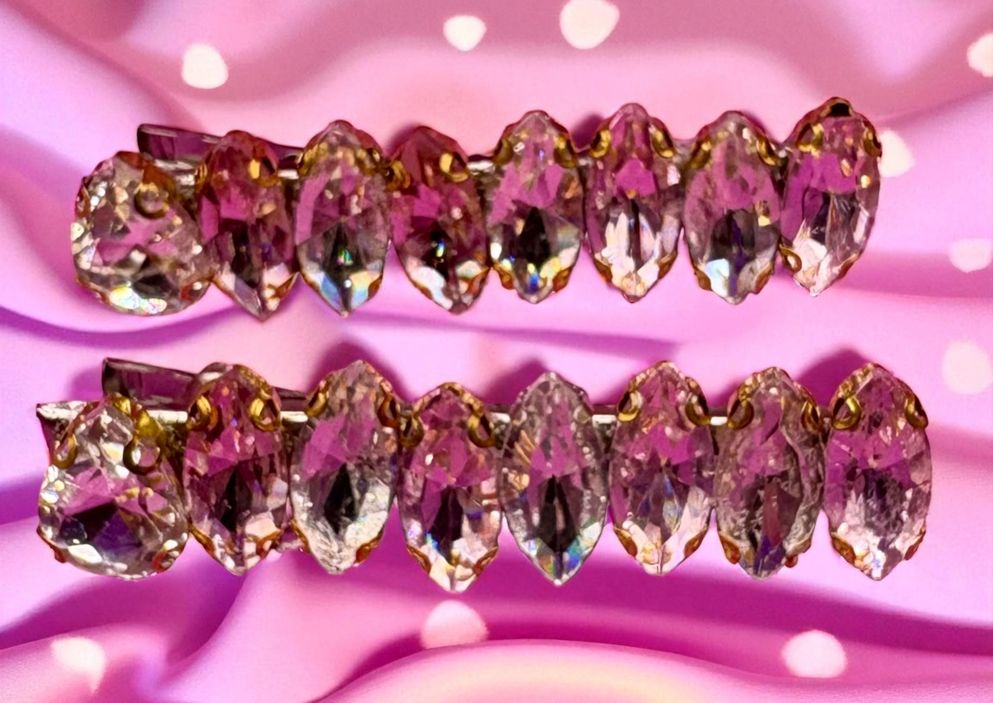 Pair of decorative hair clips with pink and gold crystals on a pink background