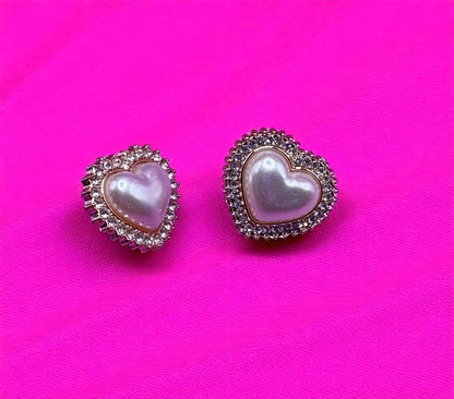 Heart-shaped earrings with pearl center on a pink background