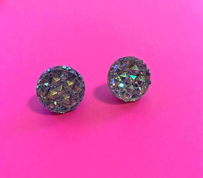 Pair of round, sparkling earrings on a pink background