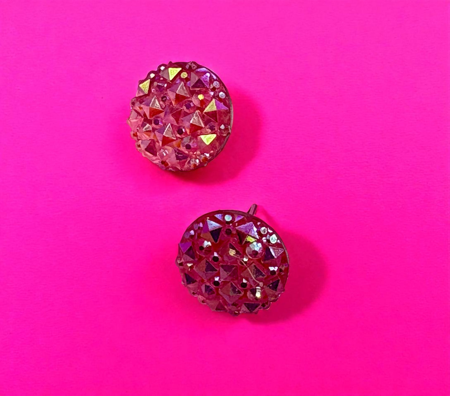 Pair of pink rhinestone earrings on a pink background