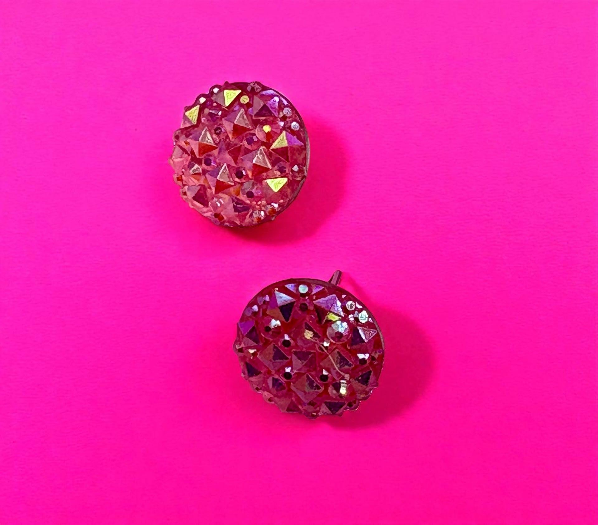 Pair of pink rhinestone earrings on a pink background