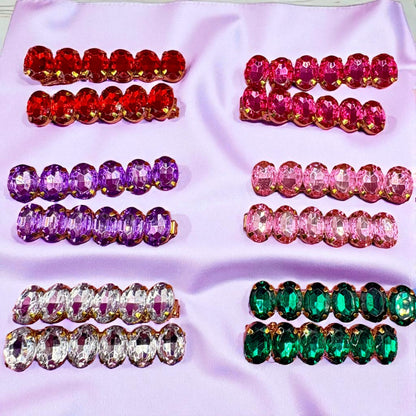Set of colorful gemstone hair clips on a pink fabric background