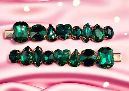 Two green gemstone hair clips on a pink background