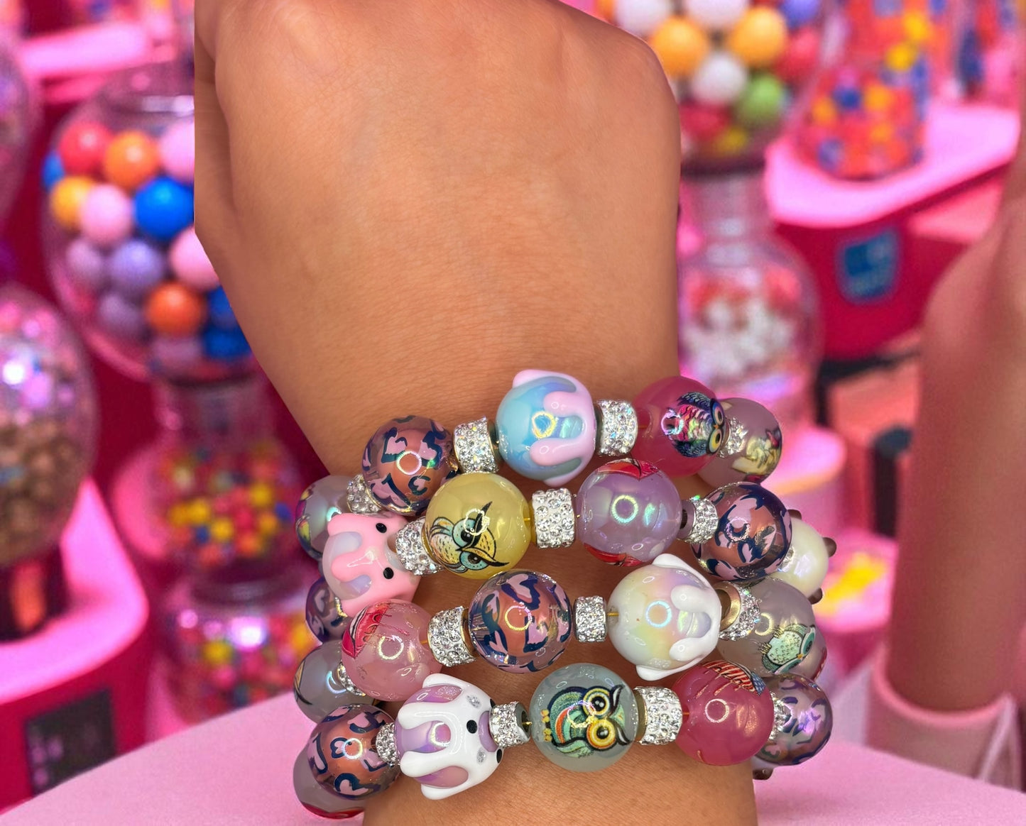 Colorful beaded bracelets on a wrist with a gumball machine in the background