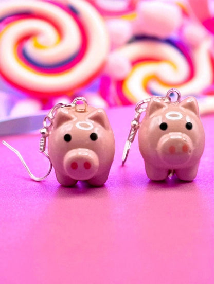 Two pink piggy bank  earrings on a pink background with colorful swirls.