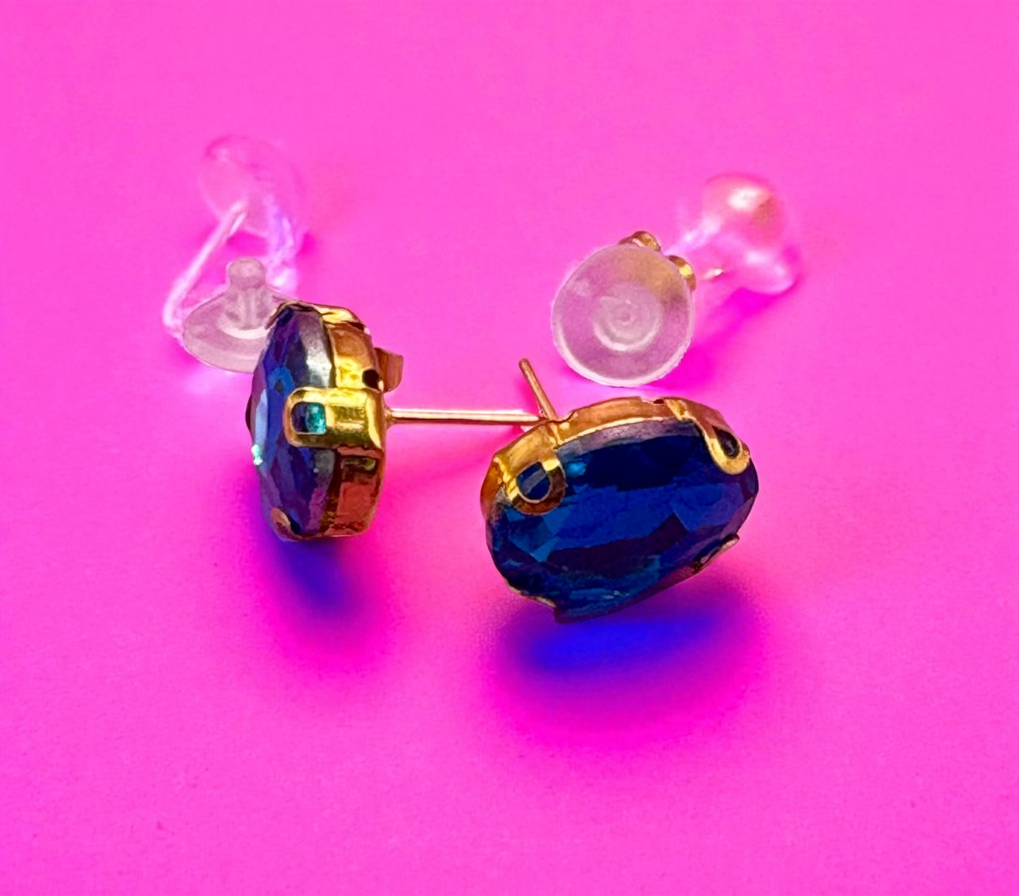 Gold and blue earrings on a pink background