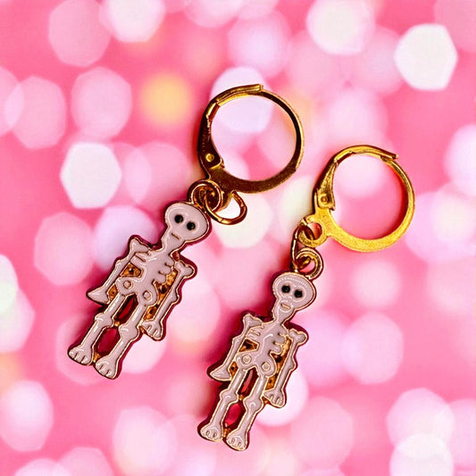 Skeleton  earrings on gold rings with a pink blurred background