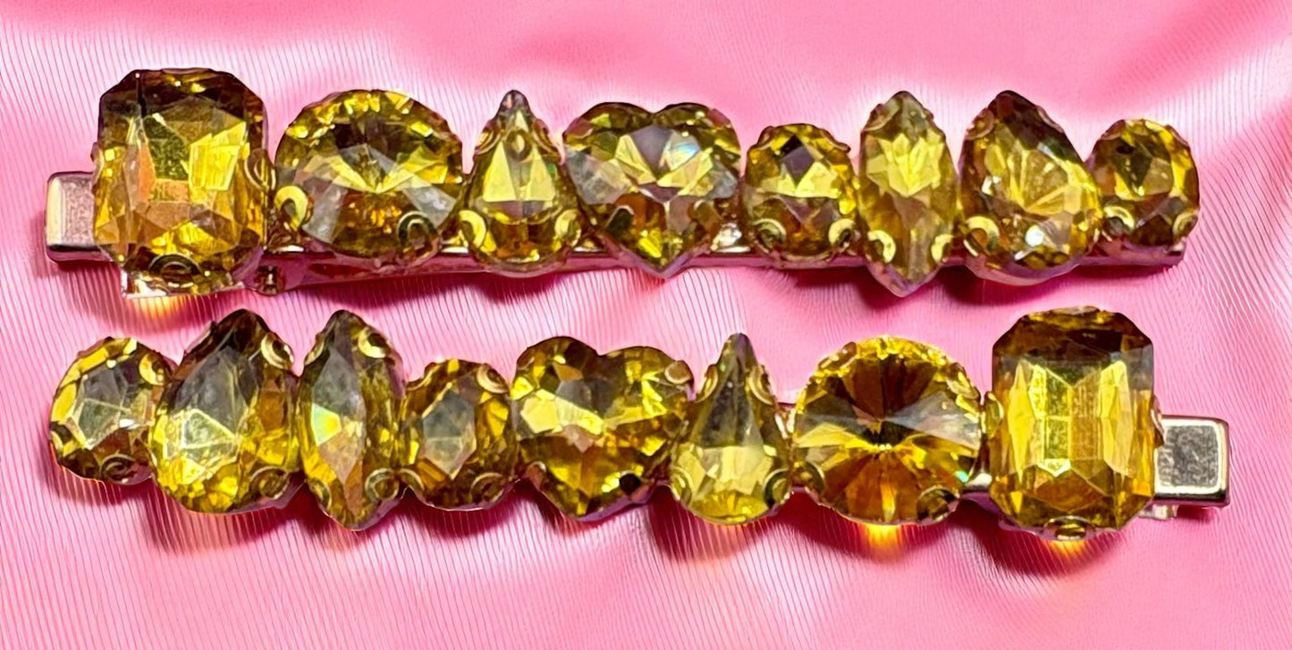 Gold hair clip with yellow gemstones on a pink background