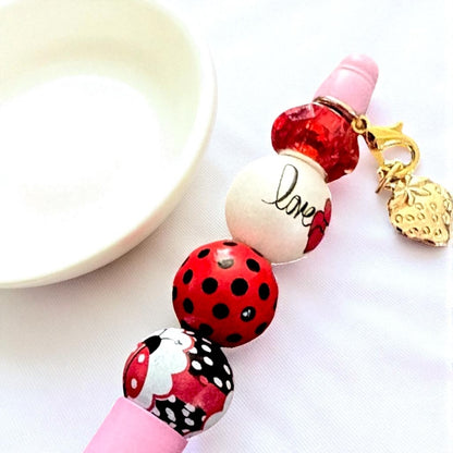 Beaded keychain with ladybug design and 'love' charm on a white background