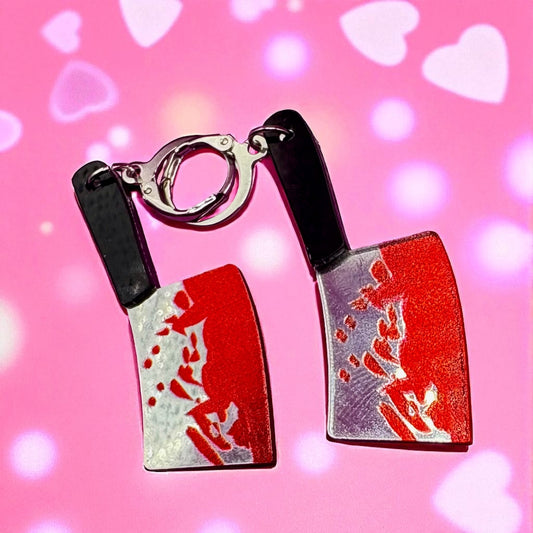 Chopstick earrings with red and silver design on a pink background with heart shapes.