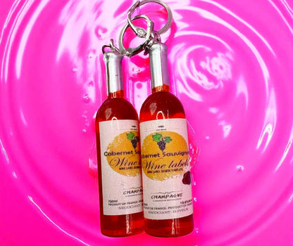 Two wine bottle  earrings on a pink background