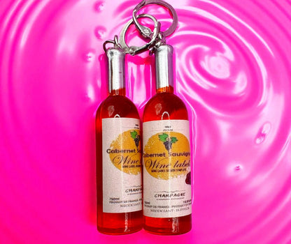 Two miniature wine bottle  earrings on a pink swirling background