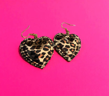 Heart-shaped leopard print earrings on a pink background