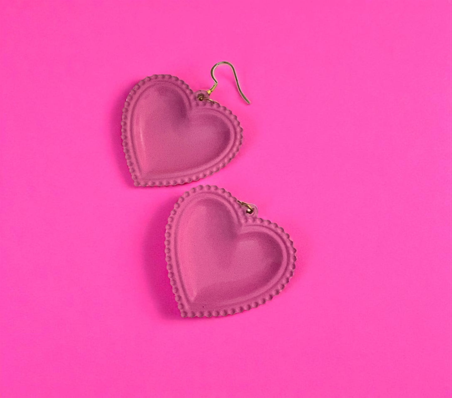 Heart-shaped earrings on a pink background