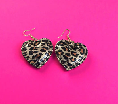 Heart-shaped leopard print earrings on a pink background