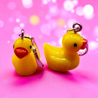 Two yellow rubber duck keychains on a pink background