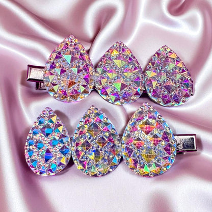 Colorful teardrop-shaped hair clips on a pink satin background