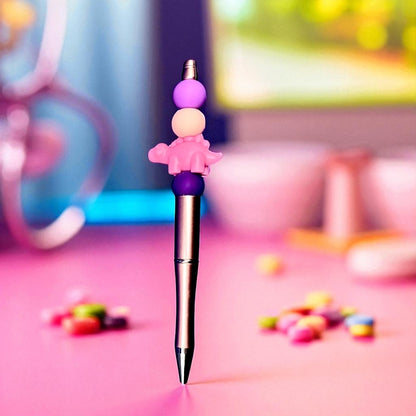 Pen with colorful character-shaped cap on a pink surface with blurred background