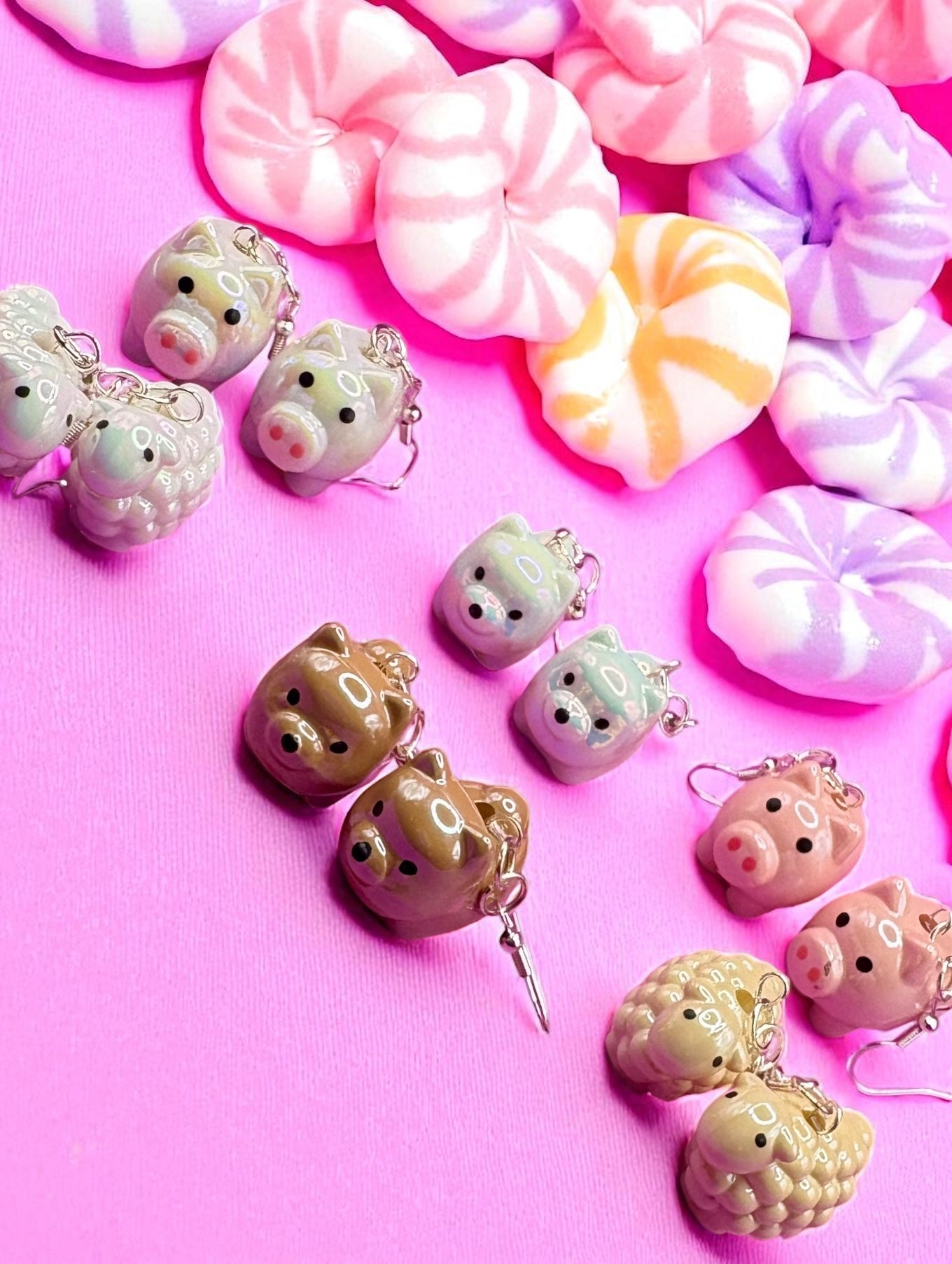 Kawaii-style piggy bank charms on a pink background