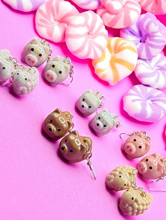 Kawaii-style piggy bank charms on a pink background