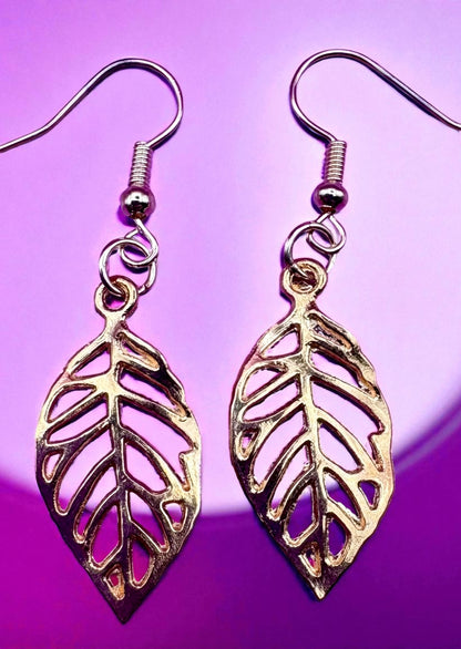 Gold leaf-shaped earrings on a purple background