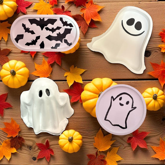 Halloween-themed ceramics on a wooden surface with pumpkins and leaves.