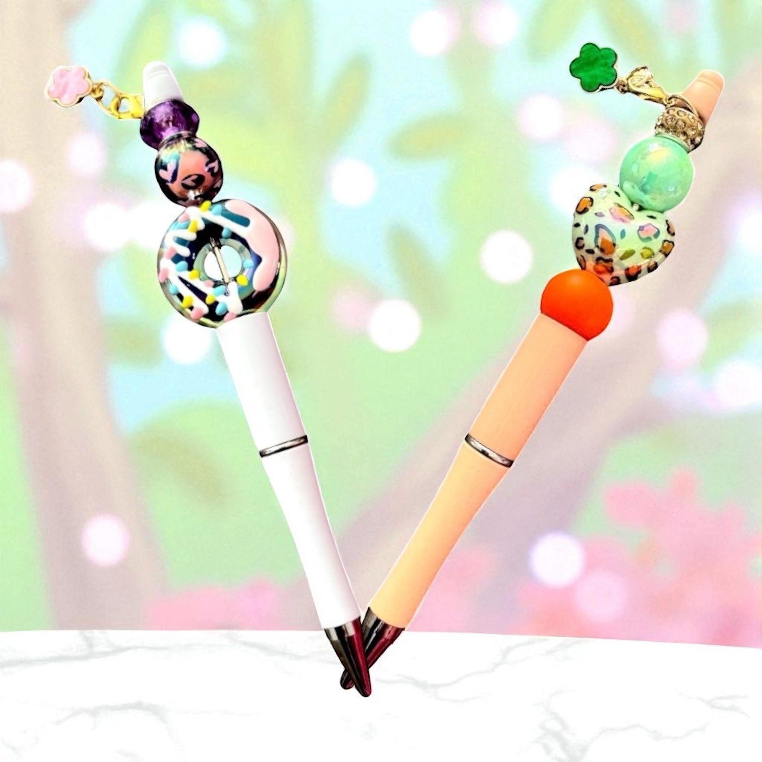 Two decorative pens with colorful beads on a blurred nature background