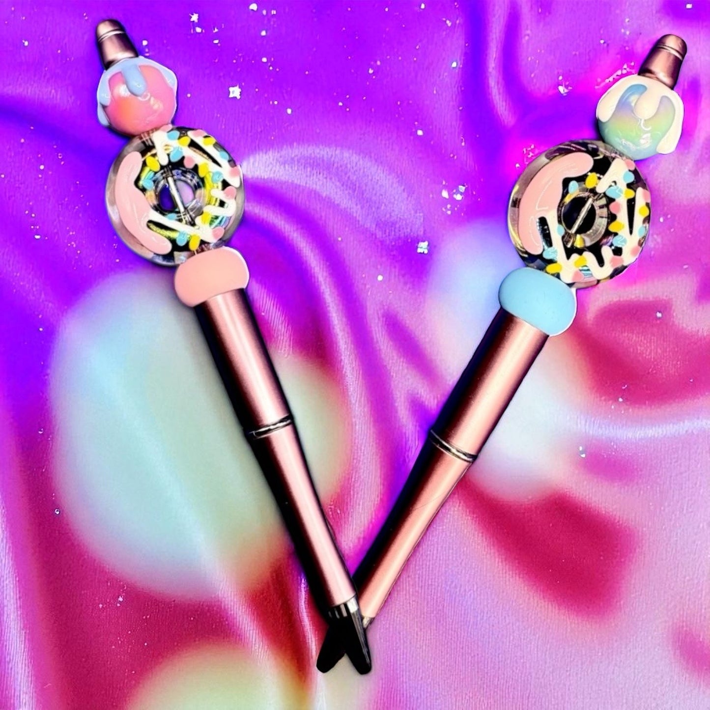 Two decorative pens with colorful designs on a vibrant, multicolored background