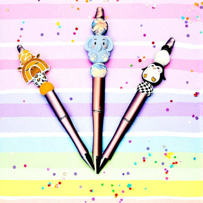 Three pens with cartoon character ends on a colorful striped background
