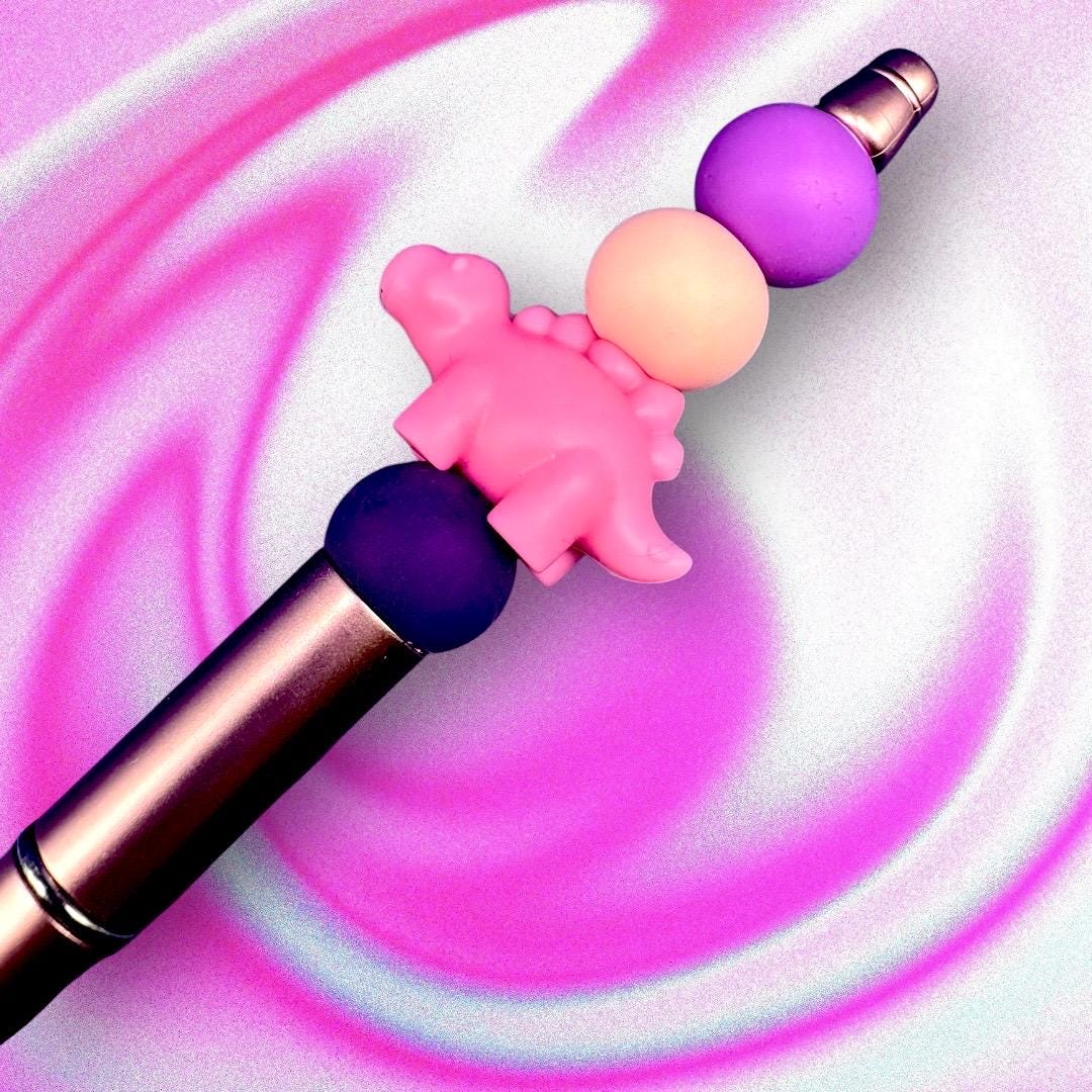 pink dinosaur pen Elevate your writing experience with our delightful Dinosaur-Themed Black Ballpoint Pens! Each pen features a whimsical design, complete with colorful beads including camouflage and adorable pink or grey dinosaur toppers, making them the perfect addition to your stationery collection or a standout gift for anyone who loves fun and functionality.