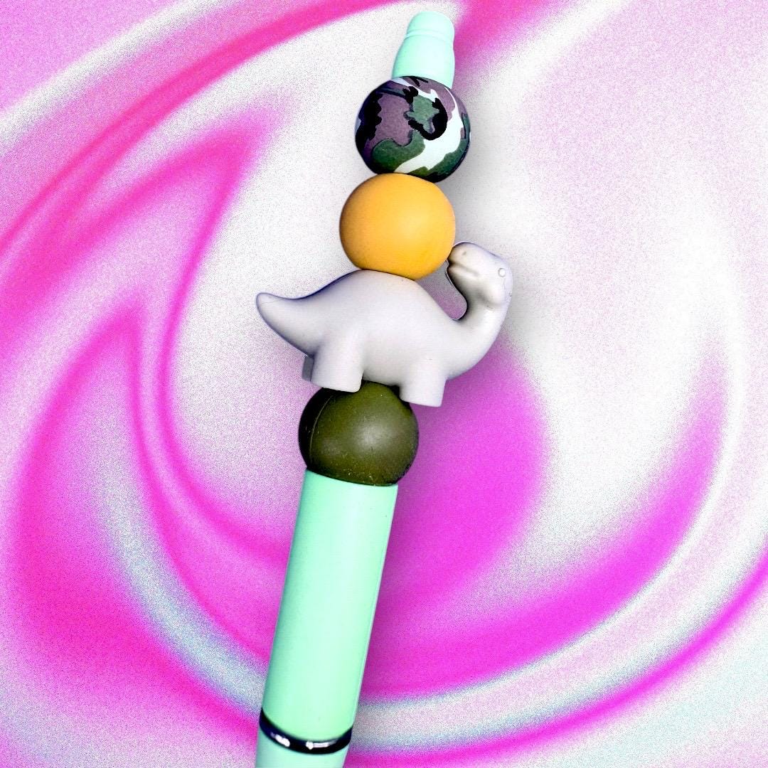 Elevate your writing experience with our delightful Dinosaur-Themed Black Ballpoint Pens! Each pen features a whimsical design, complete with colorful beads including camouflage and adorable pink or grey dinosaur toppers, making them the perfect addition to your stationery collection or a standout gift for anyone who loves fun and functionality.