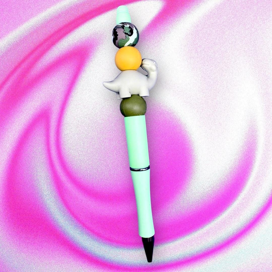 Elevate your writing experience with our delightful Dinosaur-Themed Black Ballpoint Pens! Each pen features a whimsical design, complete with colorful beads including camouflage and adorable pink or grey dinosaur toppers, making them the perfect addition to your stationery collection or a standout gift for anyone who loves fun and functionality.